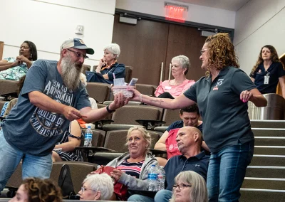 A Project31 team member handing a male participant a door prize at the 2023 breast cancer survivorship expo.