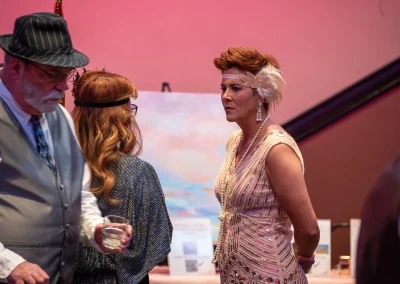 A breast cancer survivor wearing a flapper girl costume talks to guests at an awareness gala