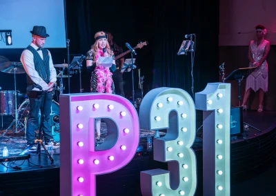 A Woman speaking on stage wearing a 1920s costume at the Paint the Town Pink gala.