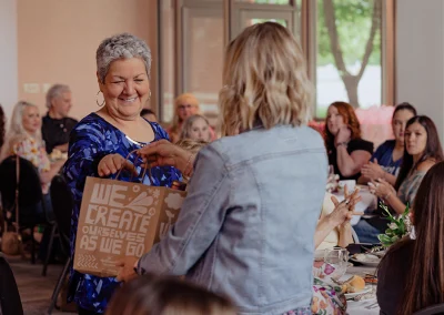 A breast cancer survivor receives a door prize at the Tulsa 2024 Survivor Luncheon.