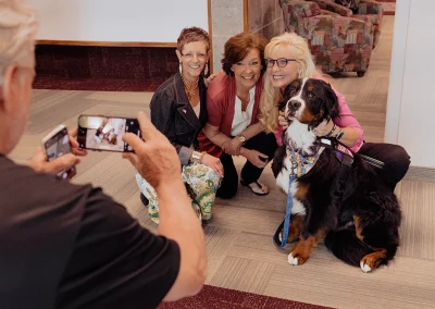 Three women smile for a photo with a Saint Bernard.