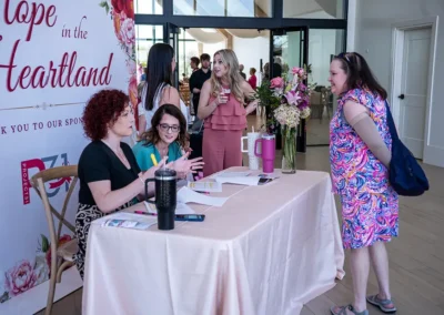 A woman talking to other women sitting at a table at a breast cancer awareness luncheon