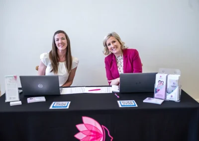 Two women sitting behind a booth on their laptops