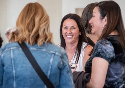 A woman smiles and laughs as she talks with other women