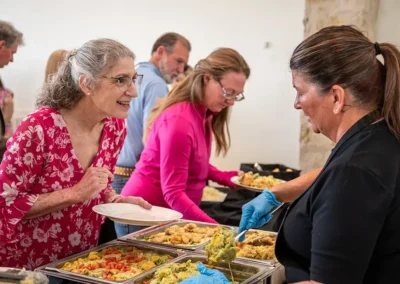 A woman leans forward and talks to another woman serving food at the event