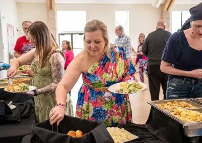A woman grabs tongs to pick up food at the event buffet