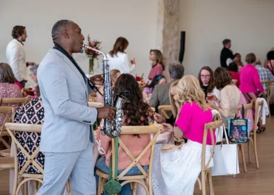 A man plays the saxophone while guests enjoy food at their tables