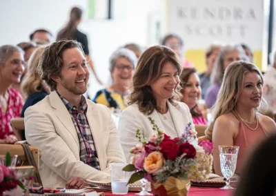 A man and woman smile as they listen to a speech being given.