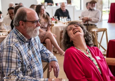A woman laughs as her husband sits next to her