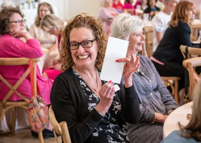 A woman holds up a piece of paper while smiling
