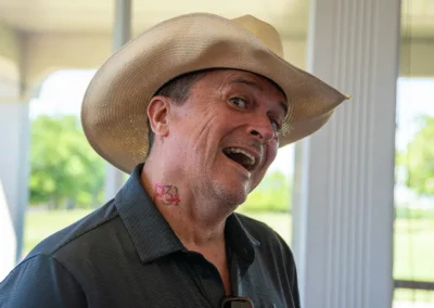 A man smiling with a P31 temporary tattoo on his neck